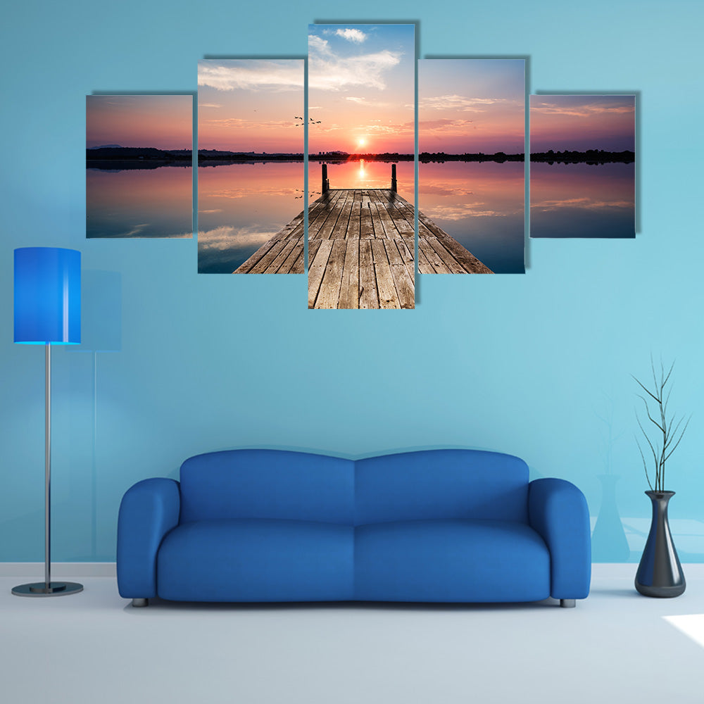 Perspective view of a wooden pier on the pond at sunset with perfectly specular reflection multi panel canvas wall art