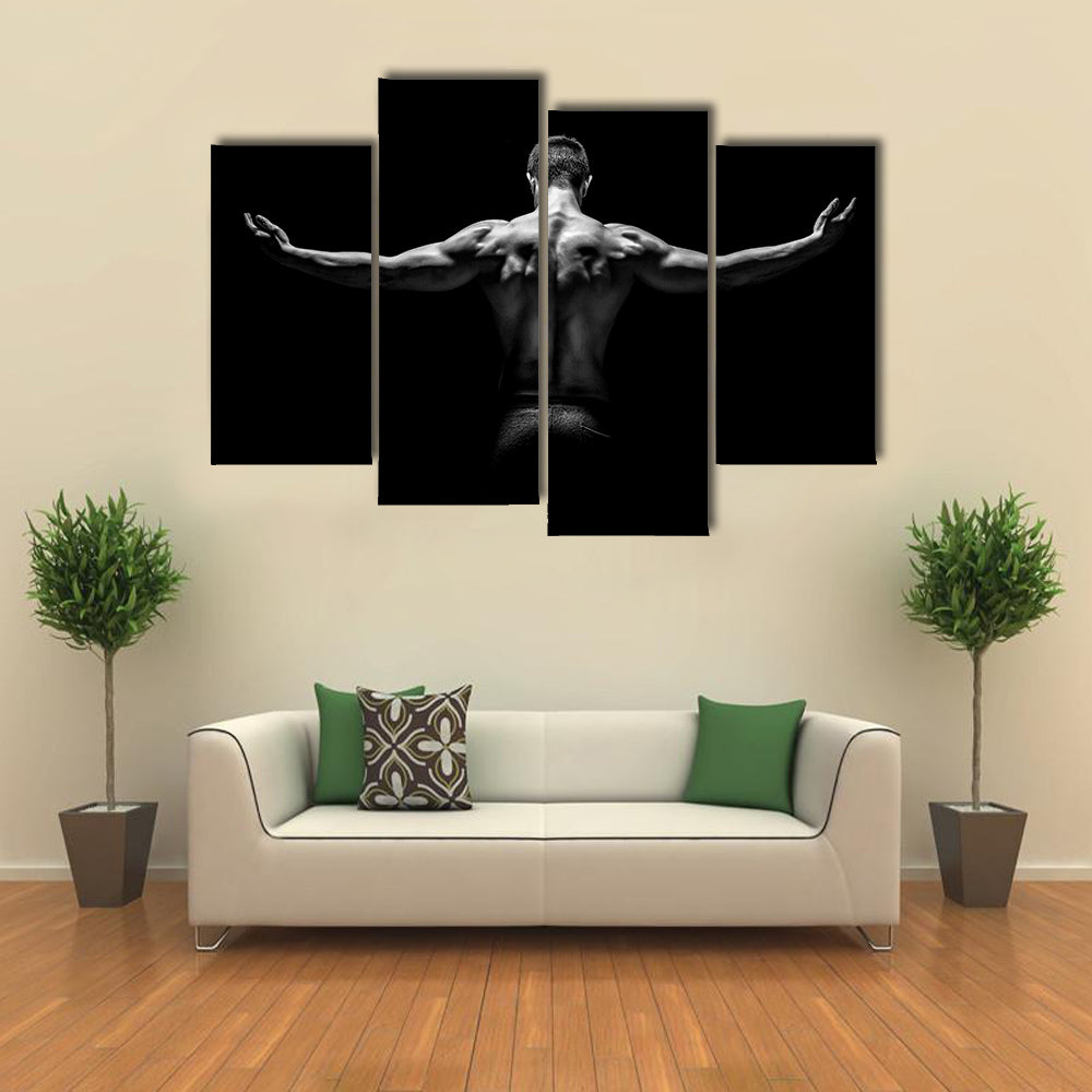 muscular young man with his arms stretched out on black background Multi panel canvas wall art