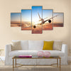 Commercial airplane flying above clouds in dramatic sunset light multi panel canvas wall art