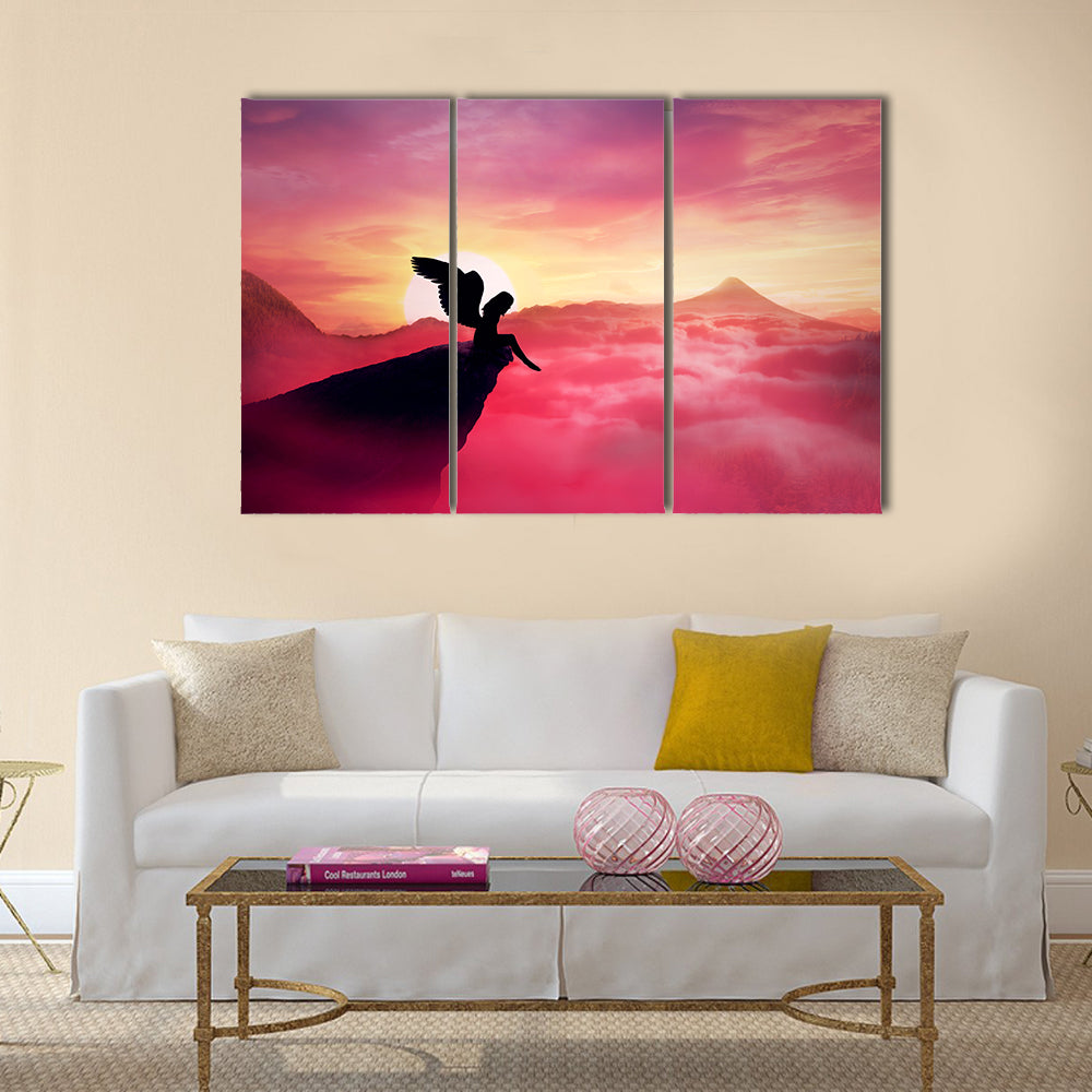 Silhouette of a lonely fallen angel with long wings standing on a cliff against a paradise sunset Multi Panel Canvas Wall Art
