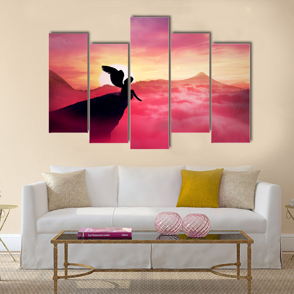 Silhouette of a lonely fallen angel with long wings standing on a cliff against a paradise sunset Multi Panel Canvas Wall Art
