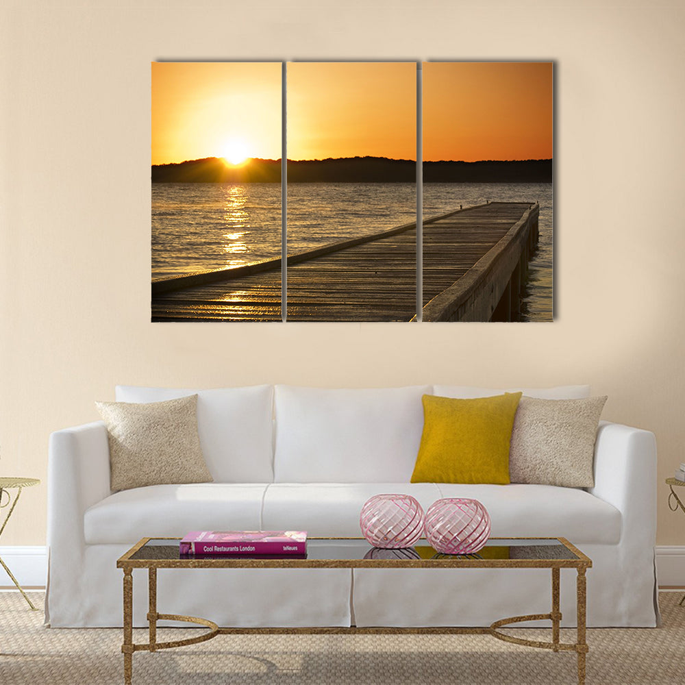 A small jetty sticks out onto the lake at sunrise multi panel canvas wall art