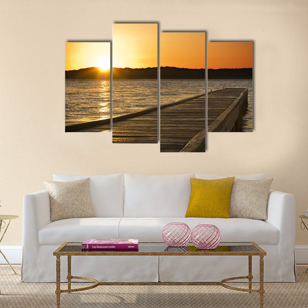 A small jetty sticks out onto the lake at sunrise multi panel canvas wall art