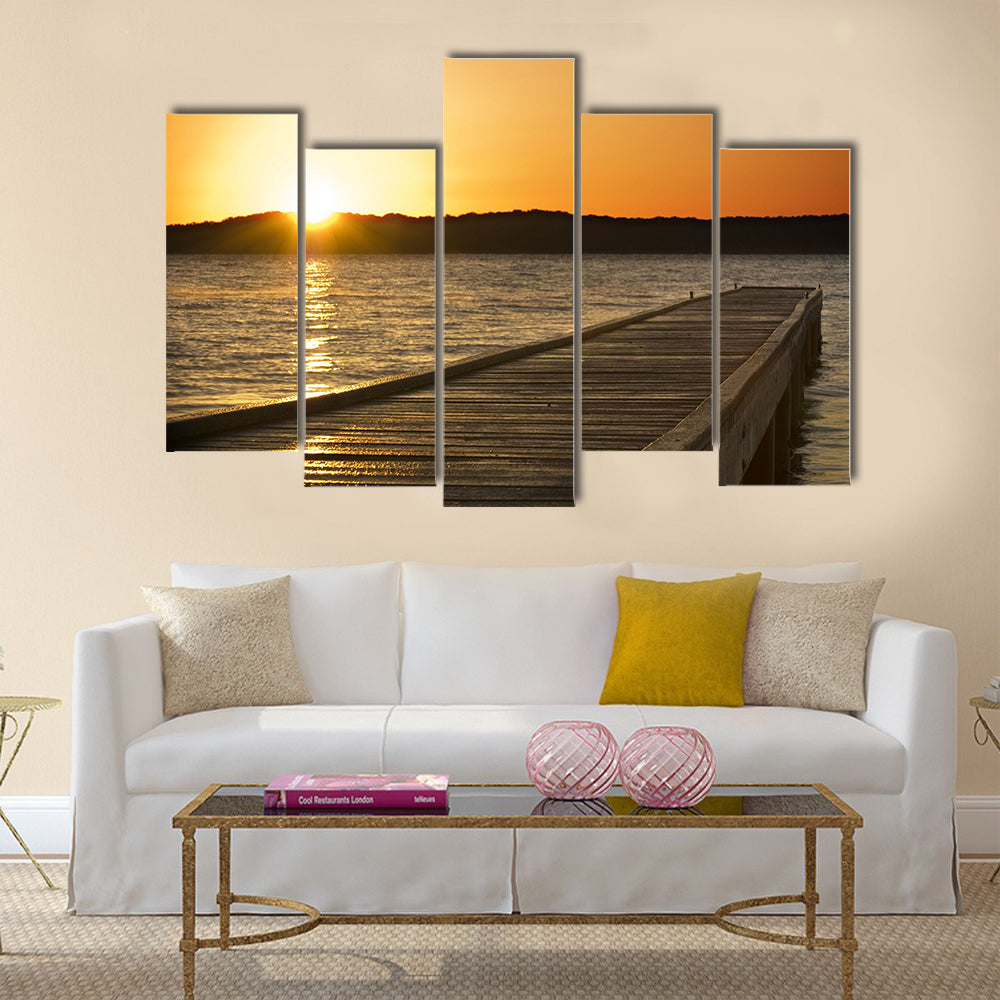 A small jetty sticks out onto the lake at sunrise multi panel canvas wall art