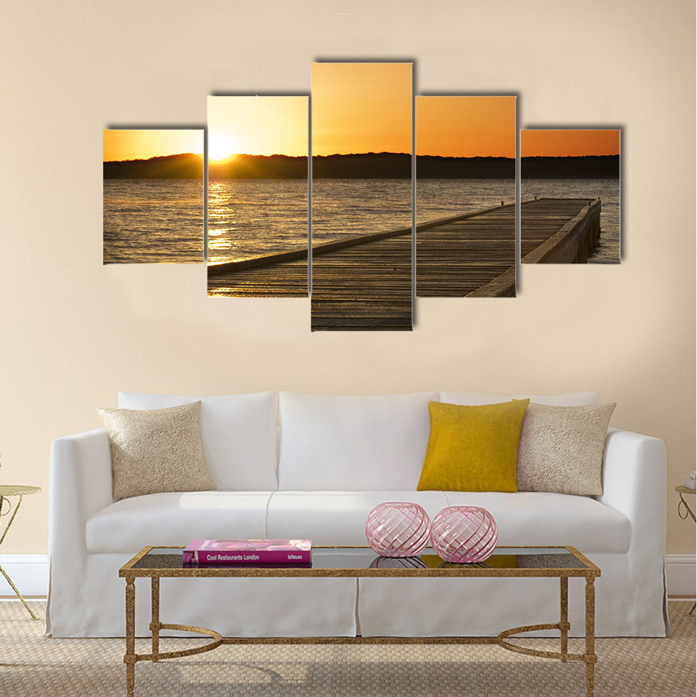 A small jetty sticks out onto the lake at sunrise multi panel canvas wall art