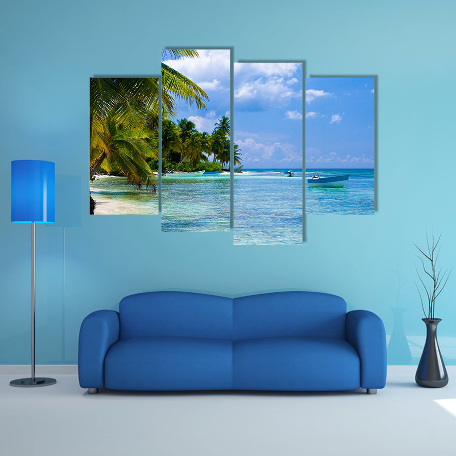 Green palms on a white sand beach with blue sky Multi panel canvas wall art