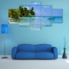 Green palms on a white sand beach with blue sky Multi panel canvas wall art