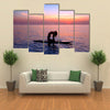 Silhouette of a yoga trainer balancing on the water on the paddle board over beautiful purple sunset Multi panel canvas wall art