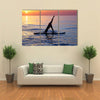 Sportive female doing yoga exercise on the beach standing on the sup board on the water in Multi panel canvas wall art