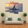 Sportive female doing yoga exercise on the beach standing on the sup board on the water in Multi panel canvas wall art