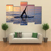 Sportive female doing yoga exercise on the beach standing on the sup board on the water in Multi panel canvas wall art