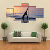 Sportive female doing yoga exercise on the beach standing on the sup board on the water in Multi panel canvas wall art