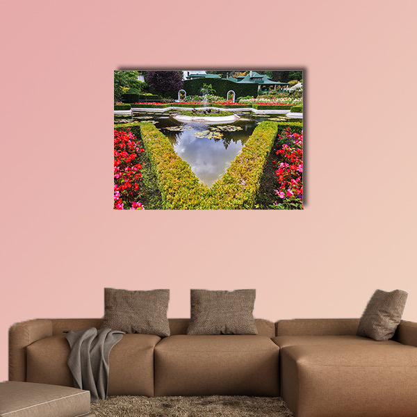 Exquisite fountain among the flower beds. Delightful landscaped wall art