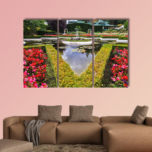 Exquisite fountain among the flower beds. Delightful landscaped wall art