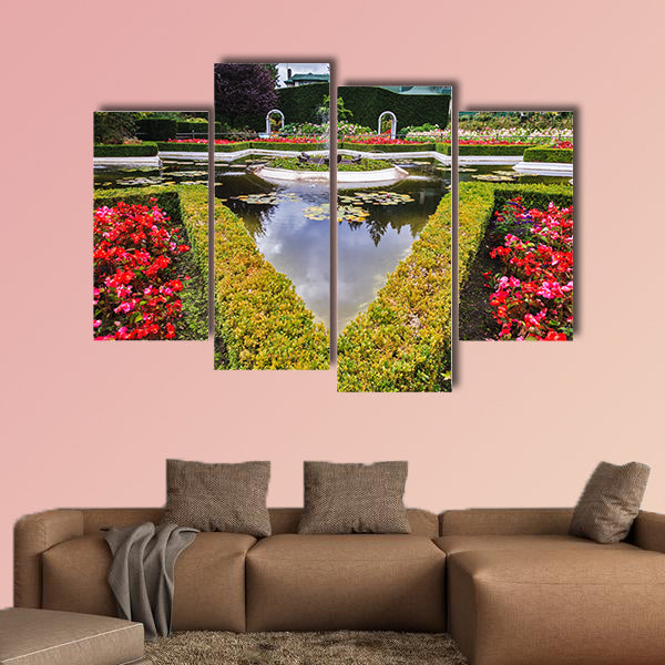 Exquisite fountain among the flower beds. Delightful landscaped wall art