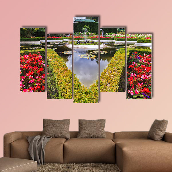 Exquisite fountain among the flower beds. Delightful landscaped wall art