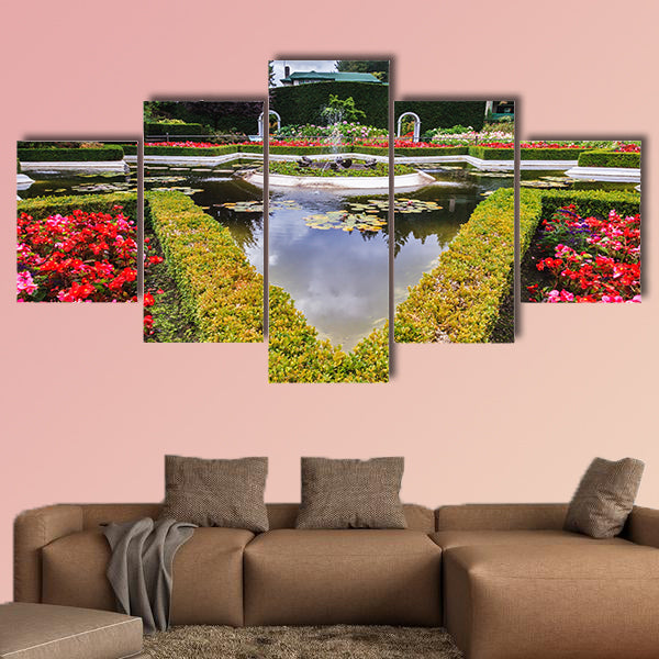 Exquisite fountain among the flower beds. Delightful landscaped wall art