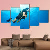 Young woman scuba diver exploring sea bottom. Underwater life with beautiful rocks and coral Multi panel canvas wall art