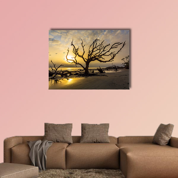 A flock of gulls flies over a driftwood covered beach at sunrise wall art