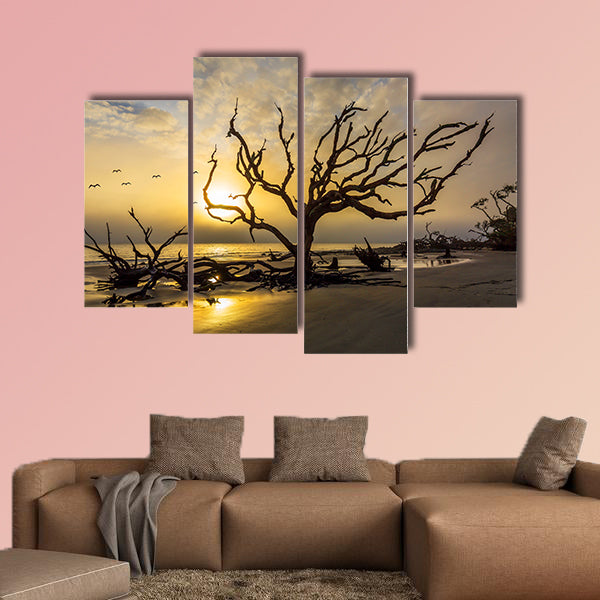 A flock of gulls flies over a driftwood covered beach at sunrise wall art