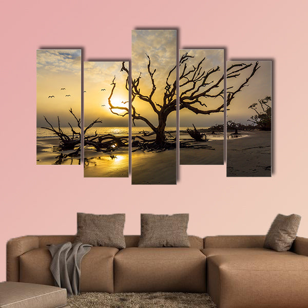 A flock of gulls flies over a driftwood covered beach at sunrise wall art