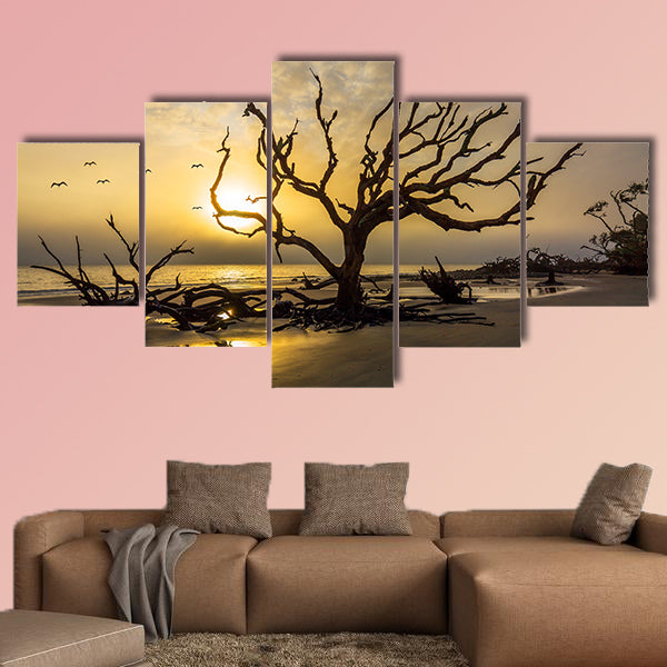 A flock of gulls flies over a driftwood covered beach at sunrise wall art