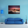 Beautiful sunset over wooden jetty with silhouette of man fishing, multi panel canvas wall art