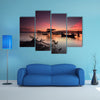 Beautiful sunset over wooden jetty with silhouette of man fishing, multi panel canvas wall art