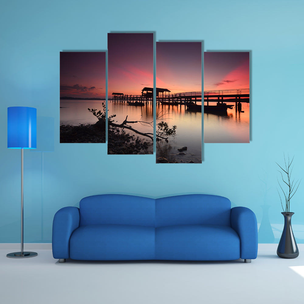 Beautiful sunset over wooden jetty with silhouette of man fishing, multi panel canvas wall art