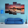 Beautiful sunset over wooden jetty with silhouette of man fishing, multi panel canvas wall art