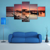 Beautiful sunset over wooden jetty with silhouette of man fishing, multi panel canvas wall art