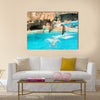 A group show of bottlenose dolphins performing a jump over water multi panel canvas wall art