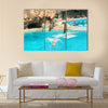 A group show of bottlenose dolphins performing a jump over water multi panel canvas wall art