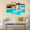 A group show of bottlenose dolphins performing a jump over water multi panel canvas wall art