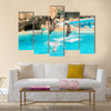 A group show of bottlenose dolphins performing a jump over water multi panel canvas wall art