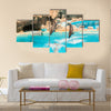 A group show of bottlenose dolphins performing a jump over water multi panel canvas wall art