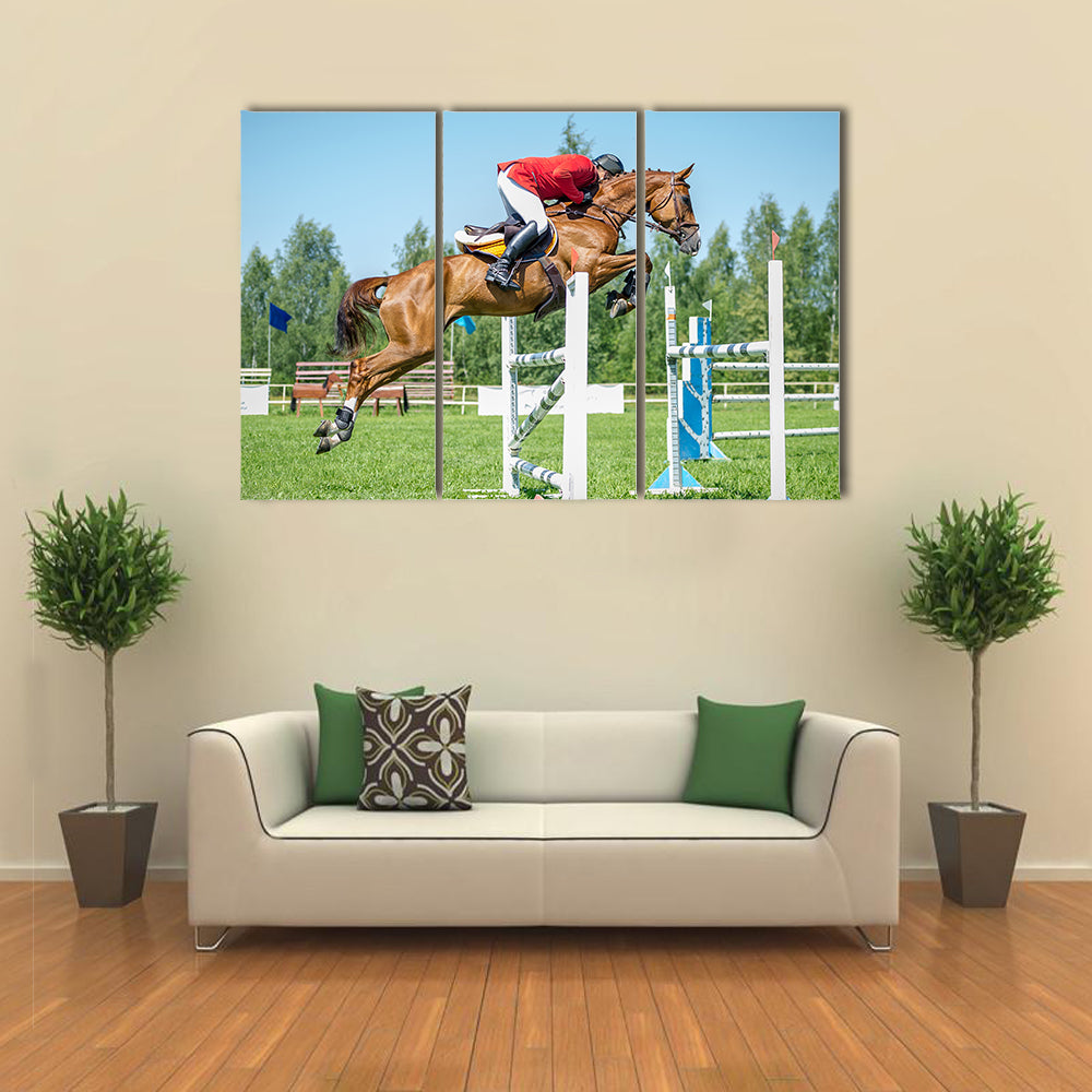 The rider on the red show jumper horse overcome high obstacles multi panel canvas wall art