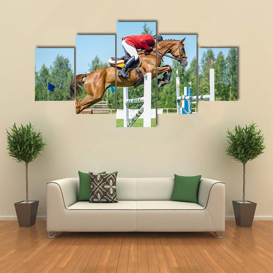 The rider on the red show jumper horse overcome high obstacles multi panel canvas wall art