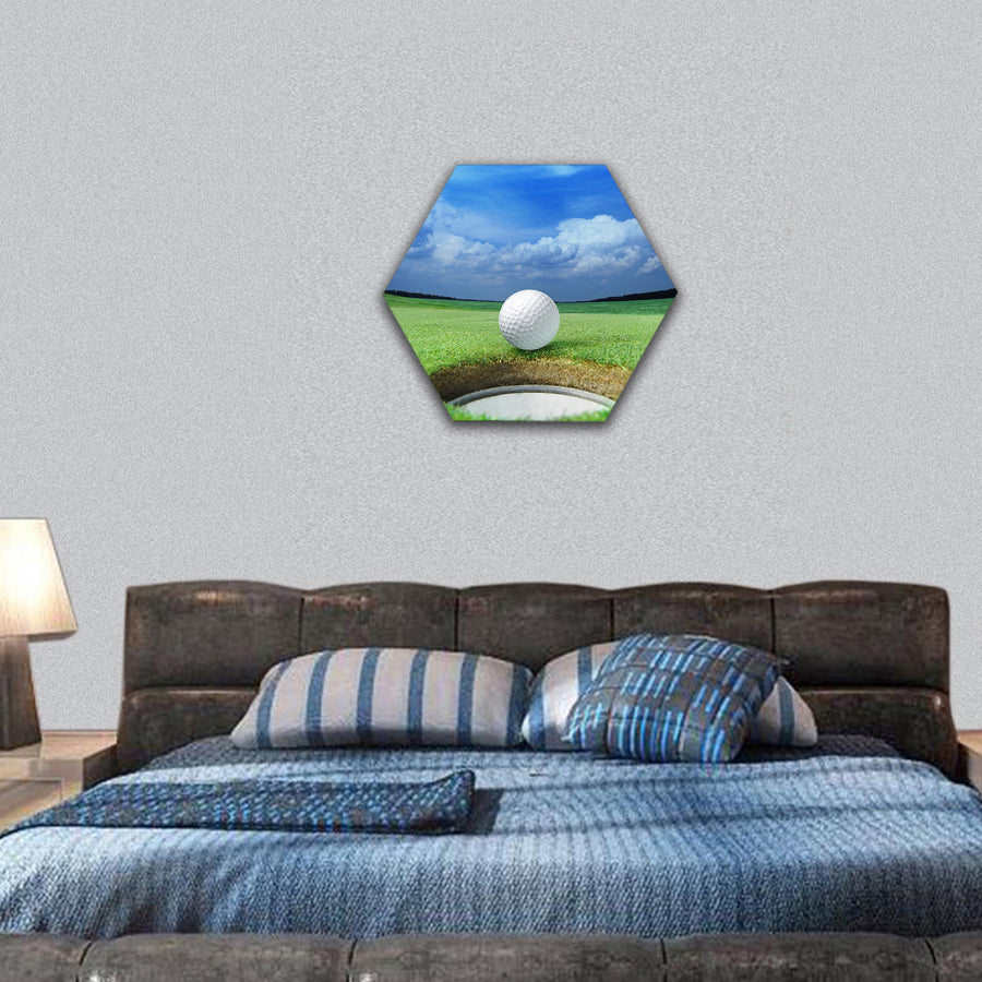 Golf ball on lip of cup of beautiful golf course hexagonal canvas wall art