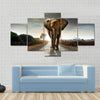 Single elephant walking in a road with the Sun from behind Multi panel canvas wall art