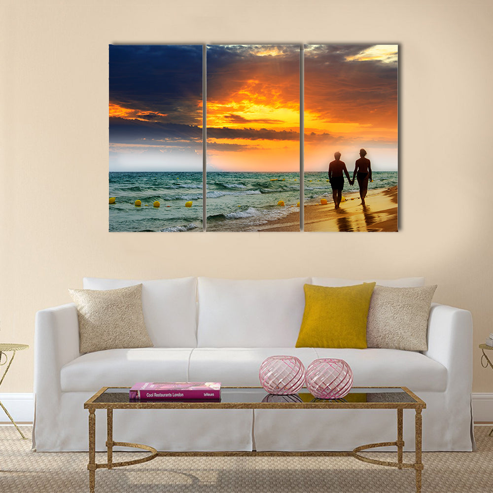 Lovers walk along the beach at sunset multi panel canvas wall art