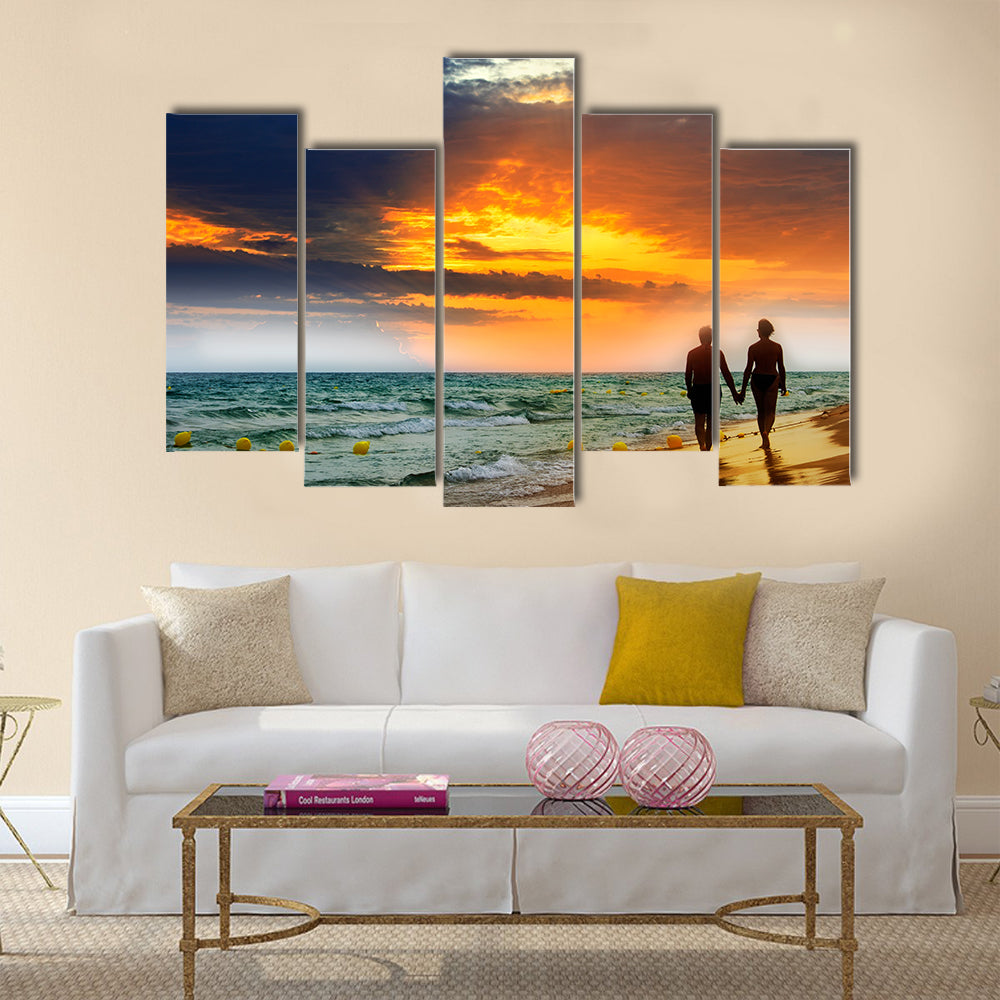Lovers walk along the beach at sunset multi panel canvas wall art