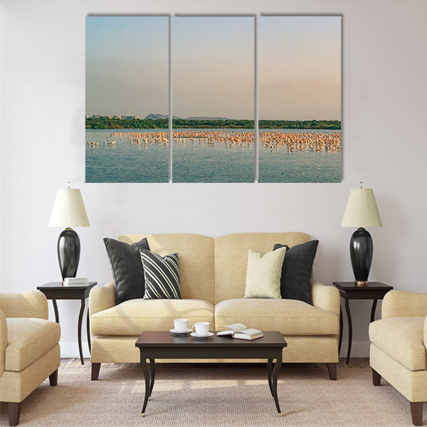 A Bunch of Flamingos Flying and Resting on a Lake Multi Panel Canvas Wall Art