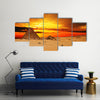 Camel caravan going through desert in front of pyramid at sunset Multi Panel Canvas Wall Art