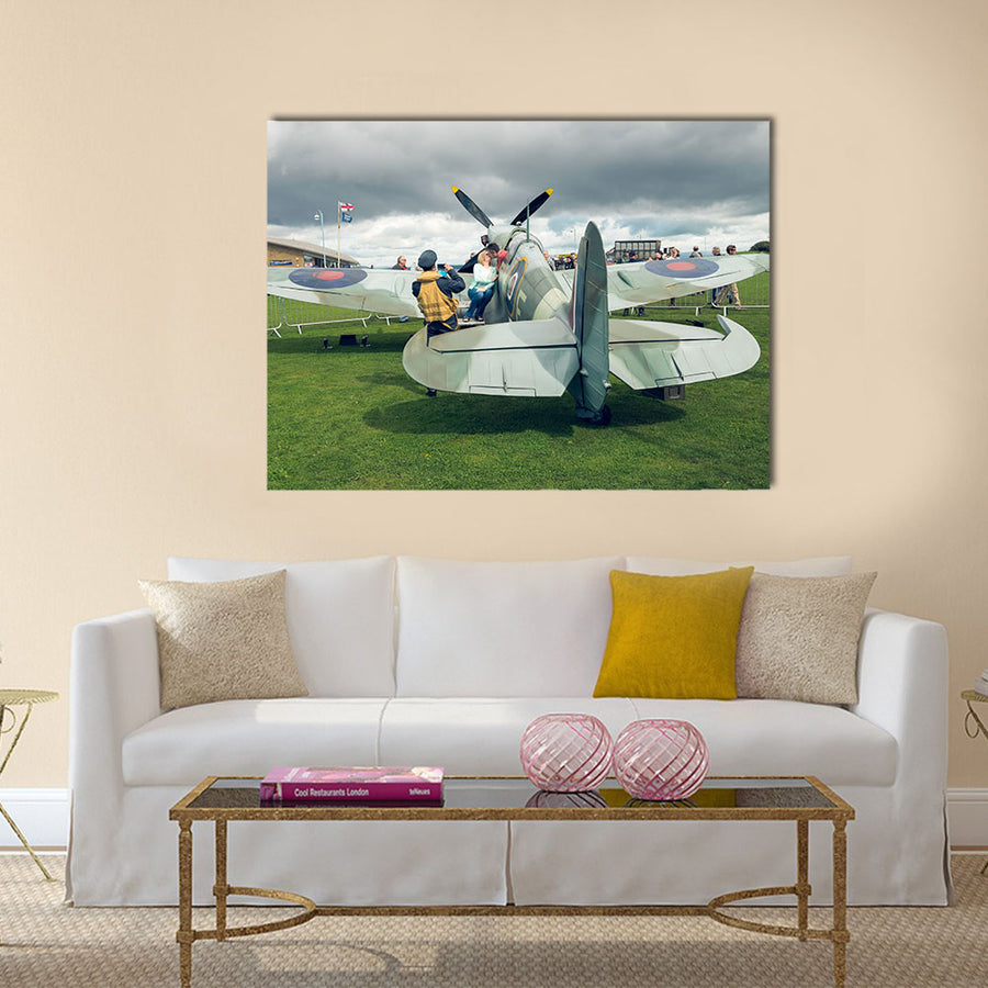 A full life size spitfire war plane replica with giant propellors, in a field on view to the public multi panel canvas wall art