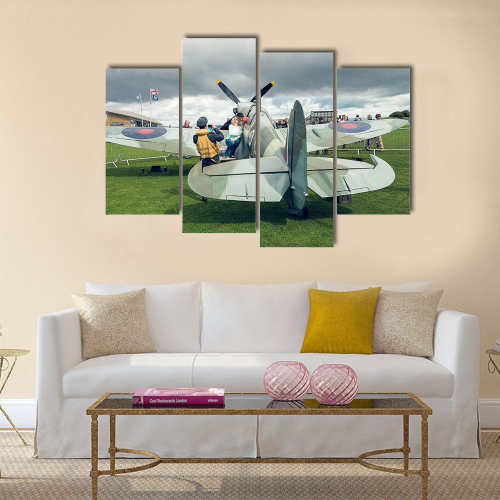 A full life size spitfire war plane replica with giant propellors, in a field on view to the public multi panel canvas wall art