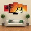 man and girl holding hands and jumping on hill near bare tree, orange background multi panel canvas wall art