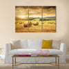 Field of freshly cut bales of hay with beautiful sunset Multi panel canvas wall art