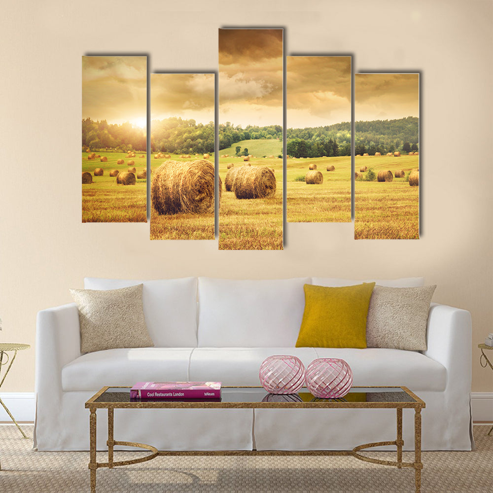 Field of freshly cut bales of hay with beautiful sunset Multi panel canvas wall art