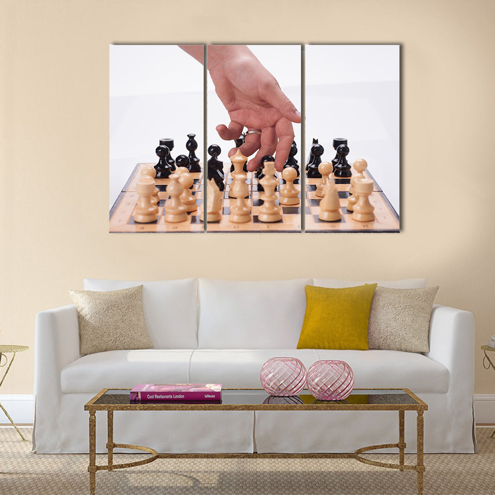 Panning shot of a chess board with a hand moving the chess pieces multi panel canvas wall art